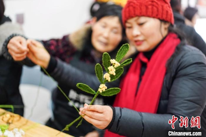 馮燕霞指導(dǎo)姐妹們鉤織月桂葉片。　古良駒 攝