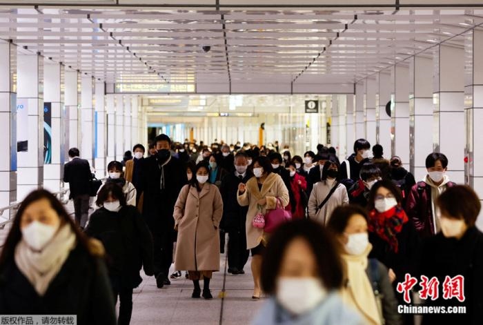 日本民眾戴著口罩走過東京一座火車站的大廳