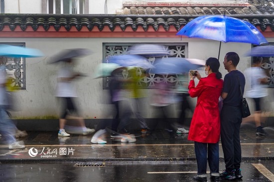 6月7日，在浙江省2023年普通高校招生考試鎮(zhèn)海中學(xué)考點，家長冒雨目送子女進入考場。人民網(wǎng) 章勇濤攝