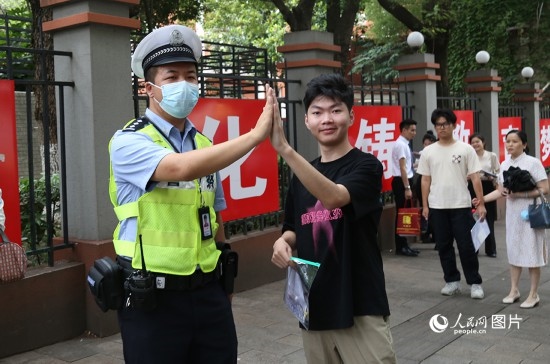 6月7日8時許，武漢中學(xué)考點門口，交警在維護秩序，并?？忌鸢耦}名。人民網(wǎng)記者 肖璐欣攝