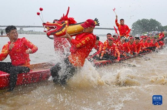 6月22日，在湖南省岳陽市湘陰縣湘江臨資口水域，參加龍舟賽的隊(duì)員接“龍頭”下水。