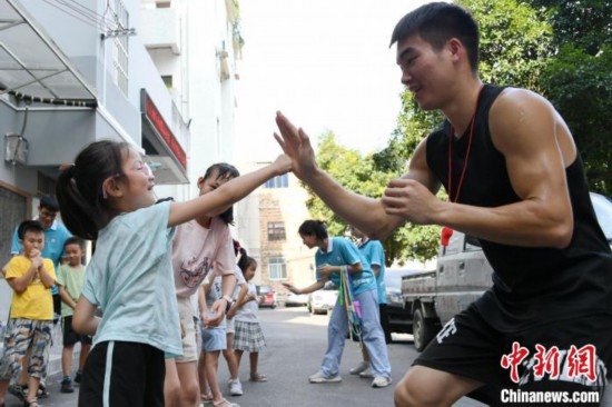 圖為大學(xué)生志愿者在組織孩子們參加體育健身活動。廖光福 攝