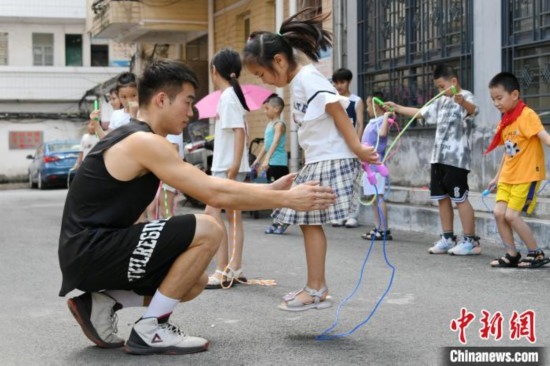 圖為大學(xué)生志愿者在教孩子們學(xué)跳繩。廖光福 攝