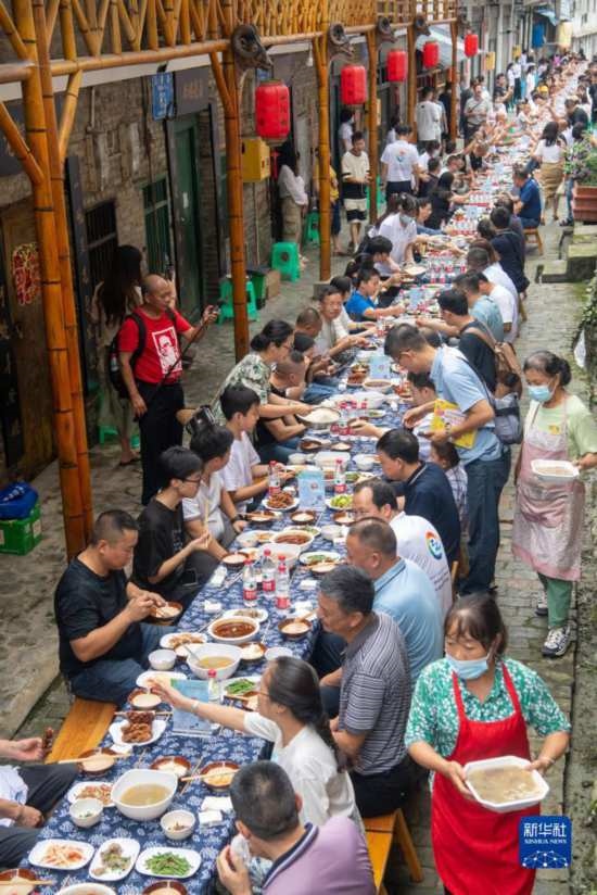 7月29日，在重慶市綦江區(qū)安穩(wěn)鎮(zhèn)，人們在“苗家伏羊節(jié)”上吃長桌宴。新華社記者 唐奕 攝