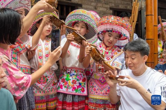 7月29日，在重慶市綦江區(qū)安穩(wěn)鎮(zhèn)，當?shù)鼐用裨凇懊缂曳蚬?jié)”上用傳統(tǒng)習俗向游客表達祝福。新華社記者 唐奕 攝