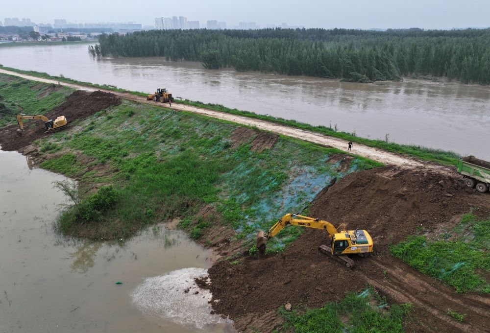 工人操作機(jī)械在白溝河左堤白溝新城高橋村段進(jìn)行除險(xiǎn)加固作業(yè)（8月4日攝，無人機(jī)照片）。新華社記者 朱旭東 攝