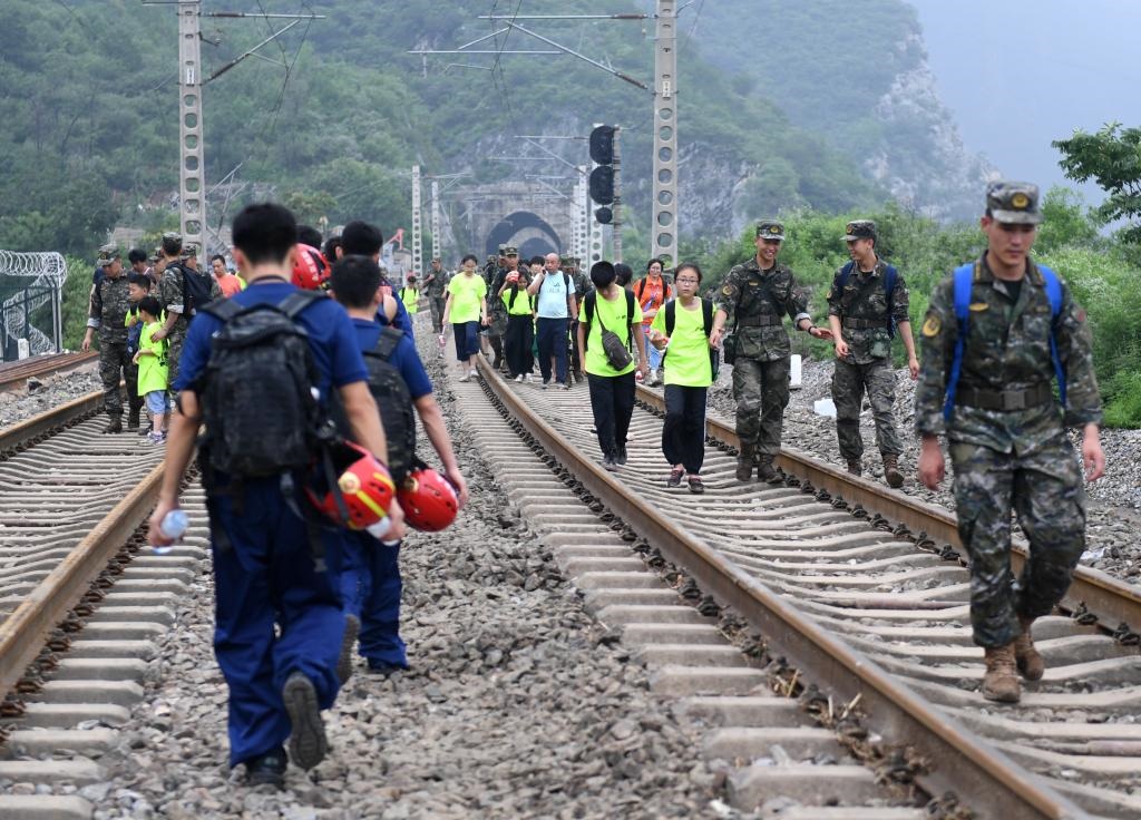 8月2日，部分滯留在北京市門頭溝山區(qū)受困列車的旅客，在救援人員幫助下前往轉(zhuǎn)運(yùn)客車。新華社記者張晨霖 攝