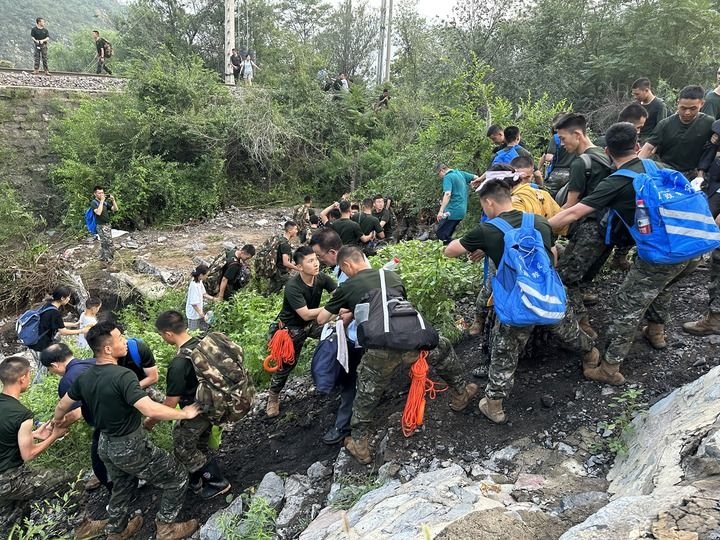 8月2日，Z180次受困列車(chē)的旅客在武警北京總隊(duì)機(jī)動(dòng)第三支隊(duì)官兵的幫助下徒步前往轉(zhuǎn)運(yùn)客車(chē)（手機(jī)照片）。新華社記者 王艷剛 攝