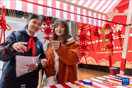 1月28日，復(fù)旦大學第二附屬學校學生（左）為美國馬斯卡廷中學學生（右）介紹中國結(jié)。 新華社記者 王翔 攝