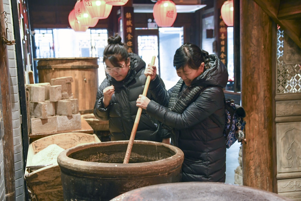 游客在平遙古城東湖老醋坊內(nèi)體驗陳醋發(fā)酵打耙（2022年1月28日攝）。新華社發(fā)（梁生仁攝）