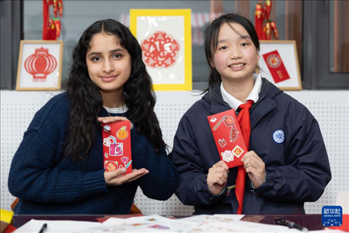 1月28日，美國馬斯卡廷中學學生（左）和復(fù)旦大學第二附屬學校學生展示互相送出的寫有寄語祝福的紅包。 新華社記者 王翔 攝