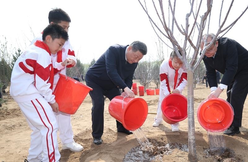 2024年4月3日，習(xí)近平總書記同少先隊(duì)員一起給剛栽下的樹苗澆水。