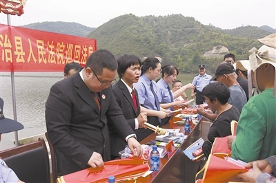 法院干警及相關(guān)部門工作人員對(duì)群眾進(jìn)行生態(tài)環(huán)境保護(hù)普法教育。