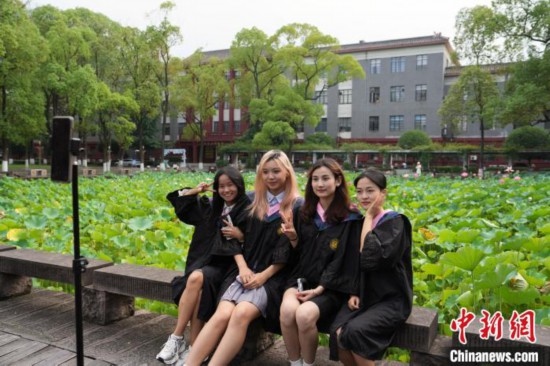 6月19日，時(shí)值一年畢業(yè)季，四川大學(xué)望江校區(qū)荷花池里的荷花盛開，成為了畢業(yè)生們的打卡圣地，吸引了眾多畢業(yè)生拍照留念。圖為畢業(yè)生在荷花池邊拍照留念。中新社記者 安源 攝