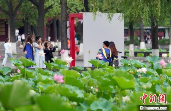 6月19日，時(shí)值一年畢業(yè)季，四川大學(xué)望江校區(qū)荷花池里的荷花盛開，成為了畢業(yè)生們的打卡圣地，吸引了眾多畢業(yè)生拍照留念。圖為畢業(yè)生在荷花池邊拍照留念。中新社記者 安源 攝