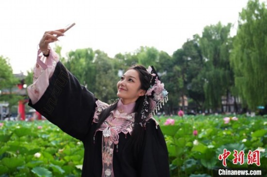 6月19日，時(shí)值一年畢業(yè)季，四川大學(xué)望江校區(qū)荷花池里的荷花盛開，成為了畢業(yè)生們的打卡圣地，吸引了眾多畢業(yè)生拍照留念。圖為畢業(yè)生在荷花池邊拍照留念。中新社記者 安源 攝