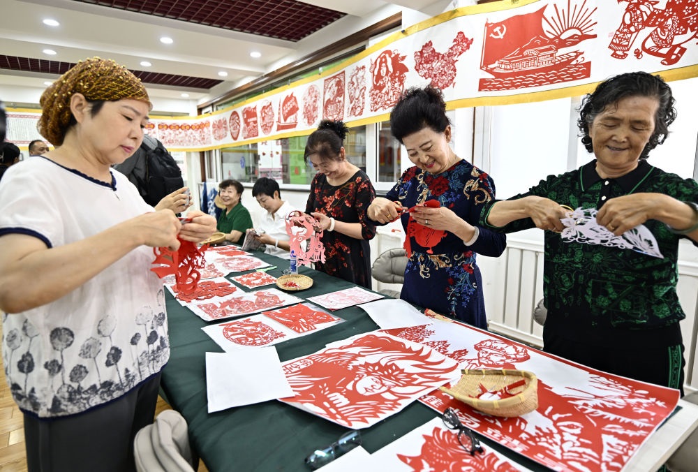 6月19日，長(zhǎng)城花園社區(qū)居民在社區(qū)“才藝堂”制作剪紙。