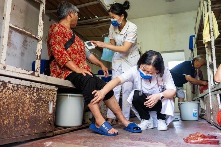 2024年7月30日，在湖南省湘潭縣河口中學安置點，醫(yī)務人員為受洪水影響而轉(zhuǎn)移安置的群眾檢查身體。 新華社記者 陳思汗 攝