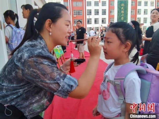 圖為衡水市利民路小學，老師為學生點朱砂痣，寓意開啟智慧。張松 攝