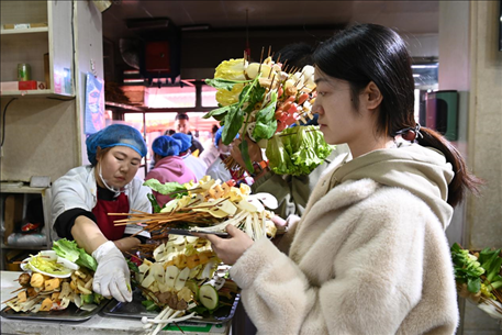 游客挑選好麻辣燙菜品后排隊(duì)等待加工。新華社記者 范培珅 攝