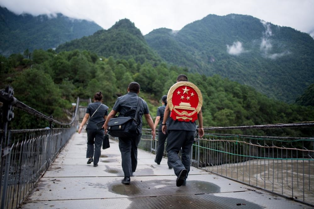 云南省怒江傈僳族自治州貢山縣人民法院法官鄧興背著國徽與同事們跨過怒江（2019年8月30日攝）。怒江高山峽谷眾多，交通不便，為方便群眾、更好地開展法律服務(wù)，背著國徽攀高山、過索橋、躲落石、鉆老林……成為鄧興法官的工作常態(tài)。新華社記者 江文耀 攝