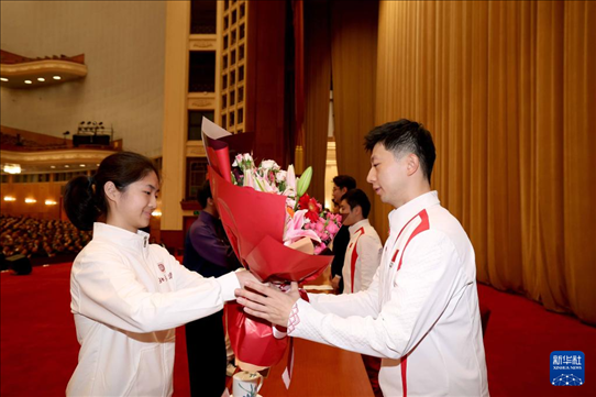 11月15日，一名學(xué)生代表在報告會上向乒乓球運動員馬龍（右）獻花。新華社記者 李明 攝